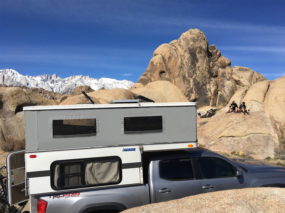 pop up truck parked in the mountains with men sitting on boulders behind it
