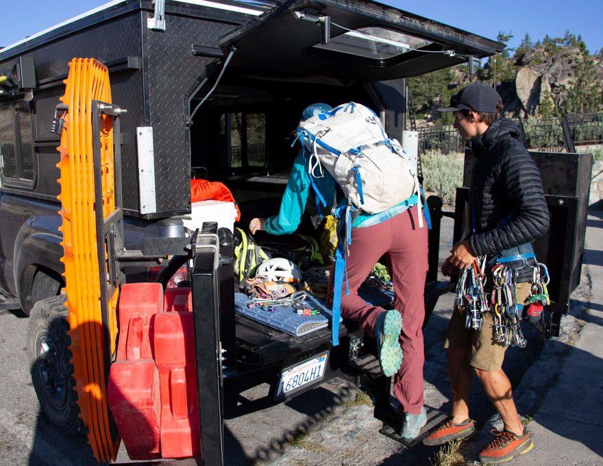 2 men with rock climbing gear getting tools ready in back of four wheel truck camper