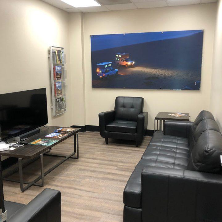 Waiting room of Four Wheel Campers of Southern California features a TV and comfortable couches.